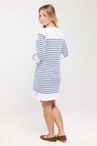 Robe en coton rayée avec des lignes horizontales bleues et blanches, manches longues, col rond et fentes sur les côtés à l'ourlet. Chaussures marron.