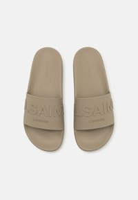 Sandales à glissière beige avec une semelle intérieure texturée. Elles possèdent une large sangle avec le texte en relief "ALLSAINTS LONDON". Fabriquées en matériau en caoutchouc doux.