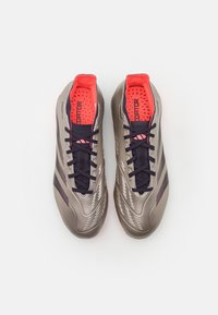 Scarpe da calcio eleganti in taupe metallico con accenti blu navy, caratterizzate da una superficie testurizzata, fodera interna di un vivace rosa brillante e lacci tradizionali.