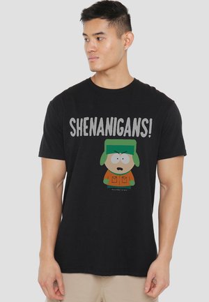 Schwarzes Baumwoll-T-Shirt mit einer Cartoonfigur, die einen grünen Hut trägt, und dem Wort "SHENANIGANS!" in fetten weißen Buchstaben darüber gedruckt.