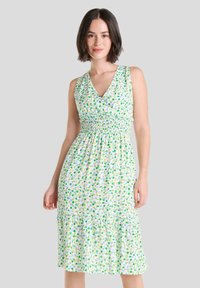 Vestido sin mangas de lunares verdes y azules con escote en V, corsé fruncido y dobladillo con volantes. Hecho de una tela ligera con un estampado floral.