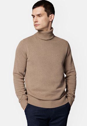 Beżowy sweter z golfem o strukturalnym splocie i dopasowanym kroju. Posiada okrągły dekolt, długie rękawy oraz małe logo na klatce piersiowej.