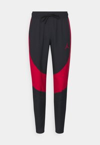 Joggers negros y rojos con cintura elástica y cordón, que presentan un diseño de panel lateral y un pequeño logo en el muslo izquierdo.