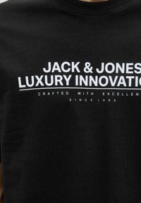 Svart bomulls T-shirt med vit tryckt text: "JACK & JONES LUXURY INNOVATION" med ytterligare mindre text nedanför. Klassisk crew neck-design.