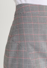 Pantaloni gray a scacchi caratterizzati da una trama tessuta con accenti rossi e un motivo a zig zag, vestibilità sartoriale con vita strutturata.