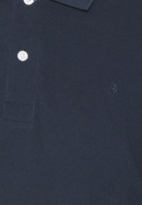 Polo shirt navy in tessuto testurizzato con colletto a coste, caratterizzato da tre bottoni bianchi e un piccolo dettaglio ricamato a forma di rosa.