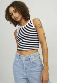 Čierno-biely pruhovaný crop top s rebrovanou textúrou, so širokým výstrihom a bezrukávovým dizajnom, v kombinácii so svetlomodrými džínsy s vysokým pásom.