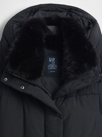 Schwarze Winterjacke mit Kunstpelzkragen, gestepptem Muster, Reißverschluss und Druckknöpfen. Innen sichtbares Etikett mit Pflegehinweisen.