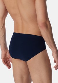 Culotte bleu marine avec une ceinture élastique lisse, design ajusté et tissu doux, montrant la vue arrière sur un fond neutre.