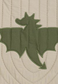 Grünes gesticktes Drachenmotif auf hellbeigem Stoff, mit genähten Details und Kurven, einer strukturierten Oberfläche und einem dreidimensionalen Umriss.