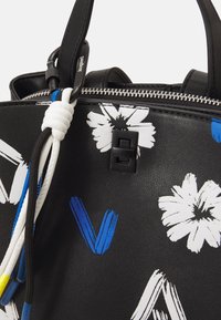 Czarna skórzana torba na ramię z białymi wzorami kwiatowymi i niebieskimi akcentami. Zawiera zamek błyskawiczny i ozdobne elementy z cordu.