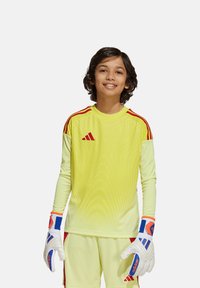 Maillot de gardien de but à manches longues jaune avec des accents rouges, motif texturé, associé à des gants blancs avec des détails bleus et rouges.