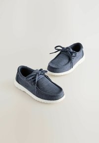 Marineblaue Segeltuchschuhe mit weißen Gummisohlen, runder Zehenpartie und Stoffschnürsenkeln. Weiches Material und strukturierte Gestaltung mit minimalen Texturdetails.