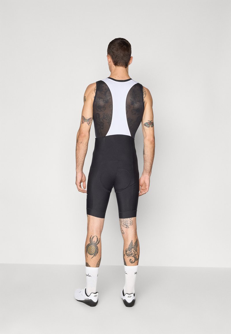 Schwarze Radsport-Bib-Shorts mit einem weißen und schwarzen gemusterten Netzrücken. Verfügt über ein enges Design und einen gepolsterten Sitzbereich für Komfort.