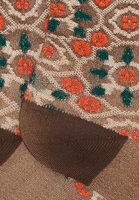 Tessuto beige a fantasia con disegni floreali arancioni e verdi, dalla superficie liscia e bordi di un marrone scuro.