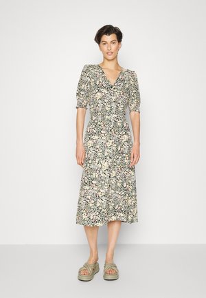 Vestido midi floral com decote em V, mangas curtas bufantes, na cor preta com padrões em rosa e verde. Combinado com sandálias de plataforma verdes.