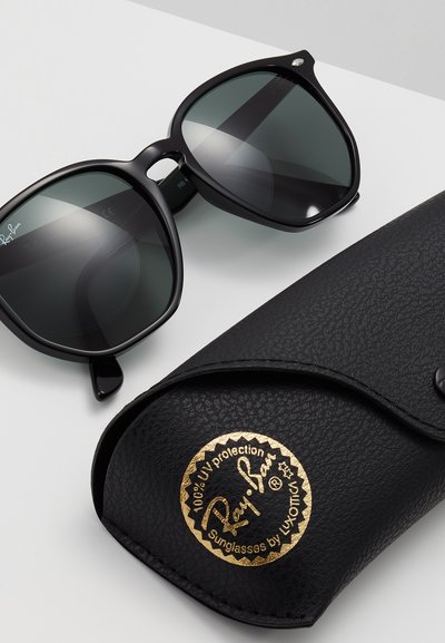 Черен модел слънчеви очила Ray-Ban с тъмни лещи, квадратна форма и носен мост. Съпроводени от текстурирана черна кутия с златисто лого.