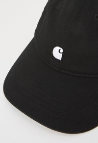 Gorra de béisbol negra de algodón, con visera curvada y un pequeño logotipo bordado en blanco. Tejido texturizado con costuras visibles.