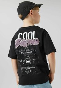 Čierne tričko s krátkym rukávom, na chrbte s odvážnym bielym a fialovým textom v grafitovom štýle, s ďalšími grafikami a detailmi striekancov.