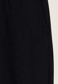 Pantalons de survêtement noirs en tissu mélangé coton. Présentent des poches latérales et un logo "FREDDY" brodé sur la jambe. Texture lisse, design décontracté.