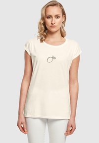 Cremefarvet T-shirt lavet af blødt stof, der har en simpel sort stregtegning af en citron med et blad, rund halsudskæring og opsmøgede ærmer.