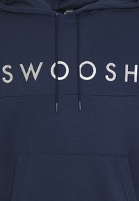 Mörkblå hoodie med stort tryck av "SWOOSH" i metallisk silver. Inkluderar en framficka och dragsnören för huvan. Mjuk tygtextur.