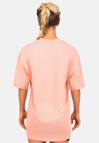 Lichtroze oversized t-shirt met korte mouwen, ronde halslijn en zachte katoenen textuur; gladde afwerking zonder zichtbare patronen of accenten.