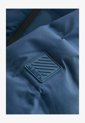 Uski blizu mornarskoplave tkanine s uzdignutom kvadratnom krpom koja prikazuje dijagonalne linije i tekst "40 26'72'' N" urezan na njoj.