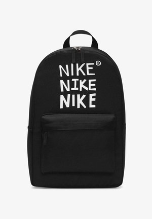 Mochila negra con bolsillo frontal con cremallera, asa superior y "NIKE" escrito tres veces en letras blancas de bloque con una pequeña carita sonriente encima.