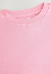 Vaaleanpunainen puuvillainen crew-neck-huppari, jonka kangas on näkyvissä ja jossa on ribbikuviointi kauluksessa.