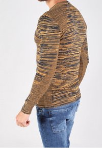 Długi rękaw, dopasowany top z teksturowanej czarno-złotej tkaniny z poziomym wzorem w paski. Posiada prążkowane akcenty wzdłuż szwów.