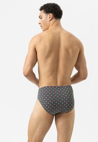 Schwimmbrillen mit einem mehrfarbigen Muster aus geometrischen Formen auf einem dunklen Hintergrund. Das Material wirkt glatt mit einem körpernahen Design.