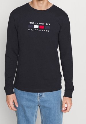 Langærmet t-shirt med rund hals i marineblåt bomuld. Har broderet "TOMMY HILFIGER"-logo med røde, hvide og blå detaljer på brystet.