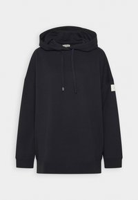 Černá oversized mikina s kapucí na šňůrky, žebrovanými manžetami a lemem a malou obdélníkovou nášivkou na levém rukávu.