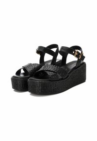 Sandalias de plataforma negras con textura trenzada en las correas, hebillas ajustables y una suela gruesa y texturizada. Acabado liso en la plantilla.