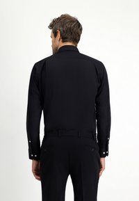 Zwart hemd met lange mouwen, gemaakt van gladde stof, met een klassieke kraag, knopenmanchetten en een aansluitende pasvorm. Subtiele stikseldetails.