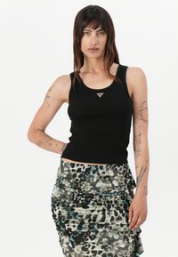 Svart ribbet tanktopp med en trekantet logo som aksent, kombinert med et plissert skjørt med et flerfarget dyreprint design.