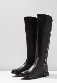 Stivali neri al ginocchio realizzati in pelle liscia, con cerniera laterale, borchie argentate lungo la cucitura e tacco basso a blocco.