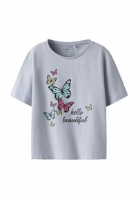 Camiseta de algodón azul claro con un gráfico de mariposa en rosa, amarillo y azul verdoso, con el texto "hola hermosa" en negro. Mangas cortas.