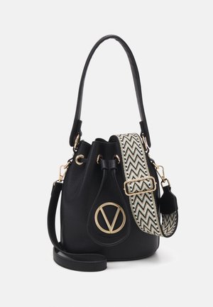 Sort læder bucket taske med guldfarvet hardware, justerbar rem med chevron-mønster og top håndtag på ensfarvet baggrund.