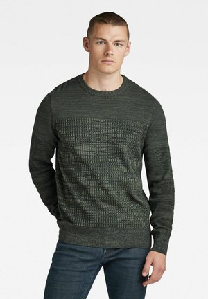 Suéter verde de punto con un diseño texturizado, que cuenta con un escote redondo y mangas largas. La tela tiene un patrón sutil, creando profundidad.