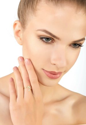 Gold ring featuring the letter "N" and a small crystal, worn on a model's hand. Smooth surface, slim band, and minimalist design.