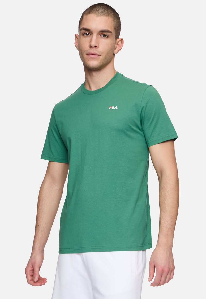 T-shirt verde in cotone con maniche corte, colletto tondo e piccolo logo FILA rosso e bianco sul petto. Tessuto morbido e vestibilità regolare.