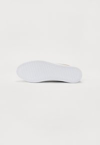 Semelle en caoutchouc blanche avec motif de grip texturé, finition lisse et bord arrondi. La base soutient un design léger, adapté à un usage quotidien.