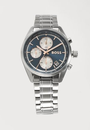 Silberne Metallarmbanduhr mit blauem Zifferblatt, drei Totalisatoren, Datumsfenster, Tachymeterskala und BOSS-Logo auf Edelstahlgliederarmband.