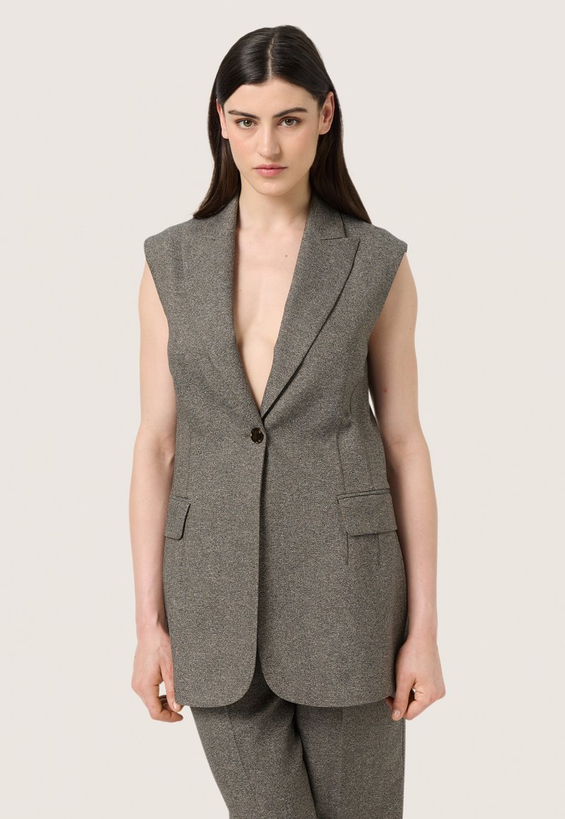 Šedý bezrukávový blazer s hlubokým výstřihem do V, jednoduchým zapínáním na jeden knoflík a dvěma předními kapsami. Texturovaná látka s jemným vzorem.