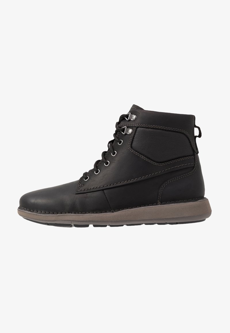 Botte montante en cuir noir avec cheville rembourrée, lacets à œillets métalliques, et semelle en caoutchouc brun clair.