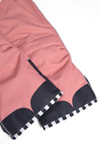 Roze stoffen shorts met een gladde textuur, voorzien van een zwart gekartelde design en een geblokte zoom. Inclusief zijzakken en stikseldetails.
