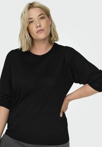 Maglione nero con scollatura rotonda, maniche a tre quarti e polsini elasticizzati. Realizzato in tessuto morbido con una texture liscia.