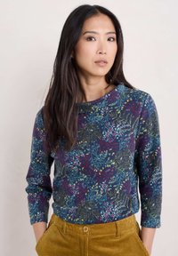 Top de manga larga en navy con un patrón floral en verde azulado, amarillo y rojo. Tejido suave con escote redondo y silueta ajustada.